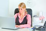 Modern business woman working on laptop at office desk
