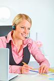 Smiling modern female manager with headset working at office
