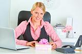 Happy modern business woman with present box at office desk

