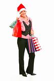 Full length portrait of smiling modern business woman in Santa Hat holding shopping bags
