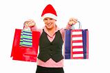 Smiling modern business woman in Santa Hat presenting shopping bags
