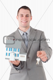 Portrait of a young businessman showing a miniature house and keys