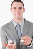Portrait of a young businessman showing a miniature house and a set of keys