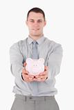 Portrait of a young businessman holding a piggy bank
