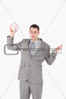 Portrait of a broke businessman shaking an empty piggy bank