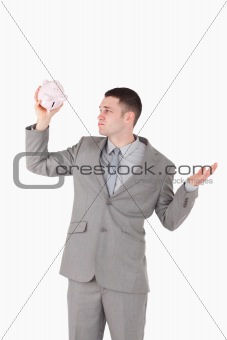 Portrait of a broke businessman looking at an empty piggy bank