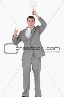 Portrait of a businessman holding a bulb above his head while pointing at something