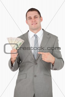 Portrait of a businessman pointing at a wad of cash