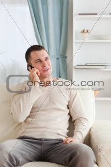 Portrait of a young man on the phone while sitting on his sofa