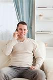 Portrait of a young man on the phone while sitting on his couch