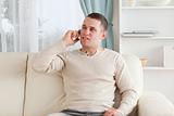 Young man on the phone while sitting on his couch