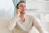 Laughing man making a phone call while sitting on a couch