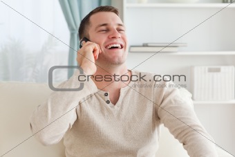 Laughing man making a phone call while sitting on a couch