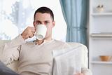 Handsome man having a tea while reading the news