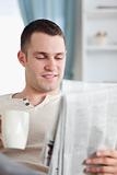 Portrait of a smiling man having a coffee while reading the news