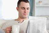 Smiling man having a coffee while reading the news