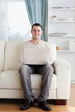 Portrait of a man using a laptop while sitting on a sofa