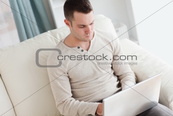 Man using a laptop while sitting on a couch