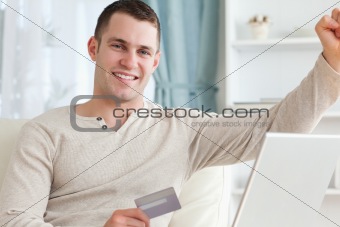 Smiling man shopping online with the fist up