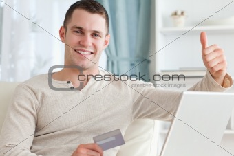 Smiling man shopping online with the thumb up