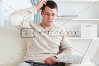 Confused man using a laptop
