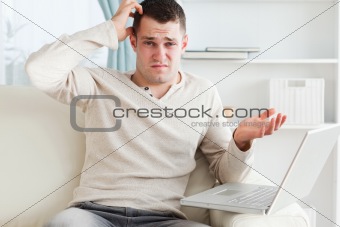 Confused young man using a laptop