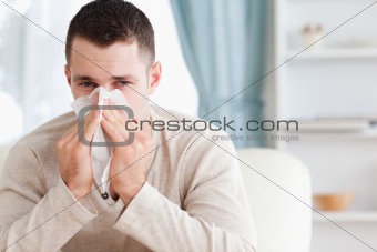 Young man blowing his nose