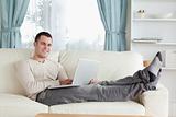 Smiling man relaxing with a laptop