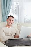 Portrait of a smiling man relaxing with a laptop