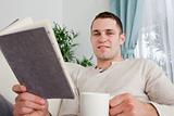 Man holding a cup of coffee and a book