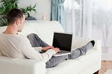 Man lying on his couch using a laptop