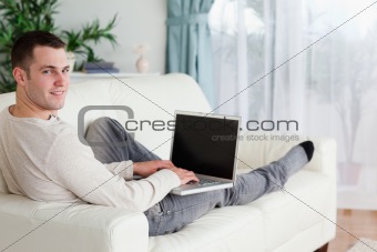 Man lying on his couch with a laptop