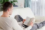 Portrait of a man lying on his couch reading a book