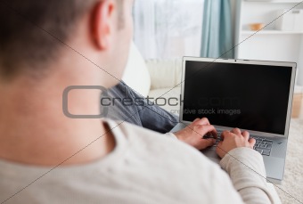 Man lying on his couch while using a laptop