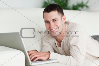 Man lying on a sofa with a laptop