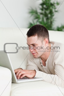 Portrait of a man lying on a sofa using a laptop
