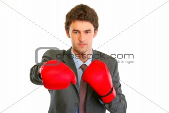 Authoritative modern businessman in boxing gloves punching
