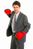 Serious modern businessman in boxing gloves brandishing to attack
