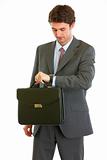 Modern businessman with briefcase checking time
