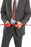 Closeup on businessman cutting red ribbon
