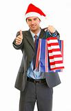 Happy modern businessman in Santa Hat with shopping bags showing thumbs up
