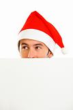 Hiding in front of blank billboard guy in Santa Hat looking in corner
