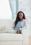Smiling woman sitting with her legs on sofa