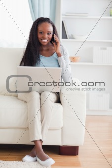 Woman with cellphone and laptop on the sofa