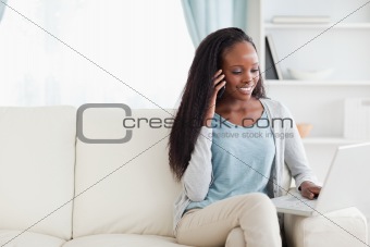 Woman with smartphone and notebook on the sofa