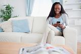 Woman writing text message while sitting on sofa