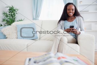Woman writing text message while sitting on couch