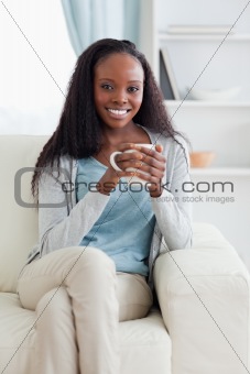 Woman with cup on her sofa