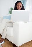 Woman working on laptop while sitting on sofa