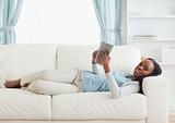 Woman lying on couch reading a book